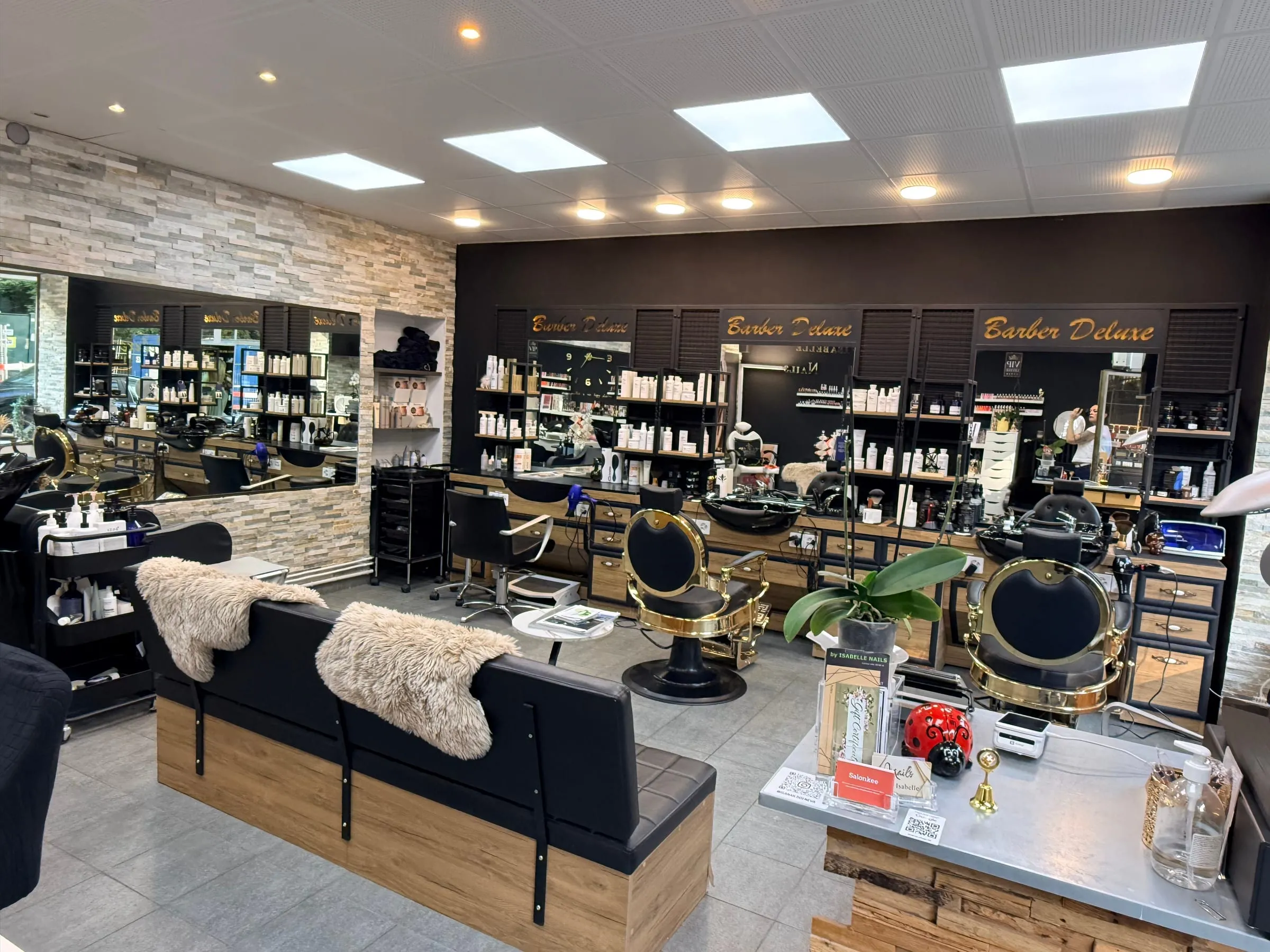 Espace barbier de Look Deluxe aux Eaux-Vives : comptoir, postes barbier, miroirs et accents dorés